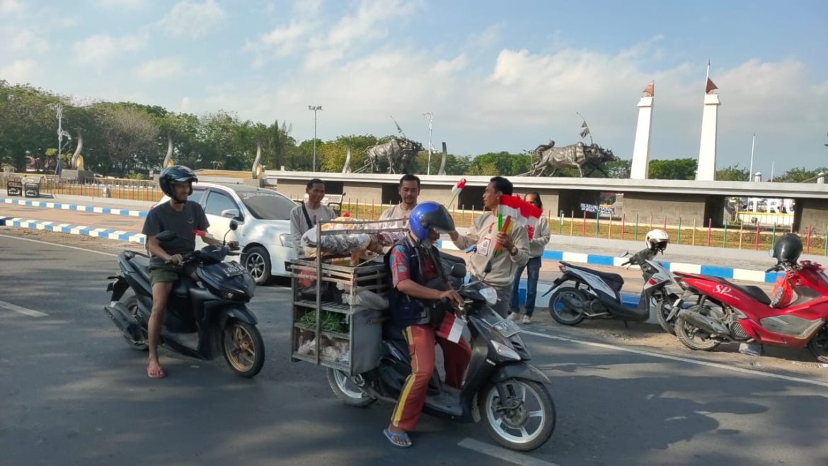 Peringati HUT RI ke-79, Aliansi Wartawan Sampang Berikan Bendera Merah Putih Kepada Pengendera yang Melintas di Alun-Alun